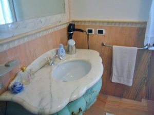 Rivestimento bagno su misura in Rosa Portogallo lucido con listello a toro rotondo fascia greca a triangoli alternando tono chiaro e scuro e relativa cornice specchio.