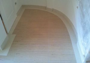 Pavimento realizzato a misura in Travertino stuccato a resina trasparente con fascia perimetrale in Bianco Perlino lucido.