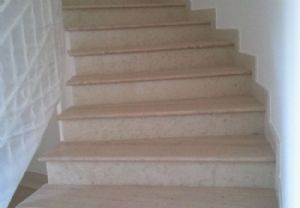 Scala sagomata su misura in Travertino stuccato a resina trasparente e lucidata cm3 con toro rotondo alzata e battiscopa in Bianco Perlino lucido.