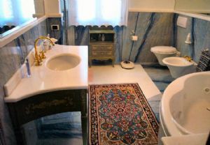 Rivestimento bagno in Azul Macaubas lucido a macchia aperta con listello piano lavano e inserto a pavimento con arcatura interna per spazio vasca in Bianco cristallino.